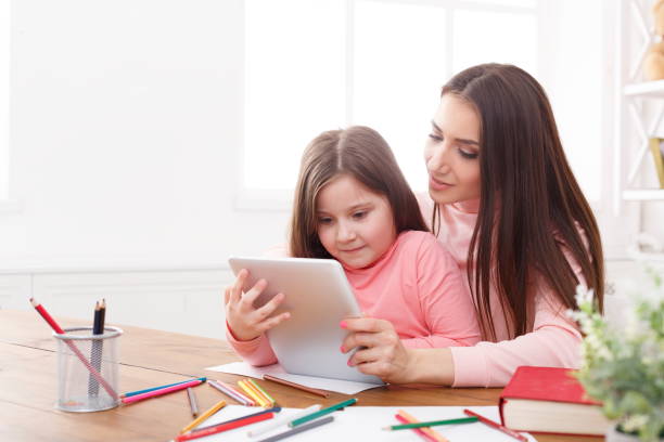 istock Little girl and her mom using a tablet at home 918073560