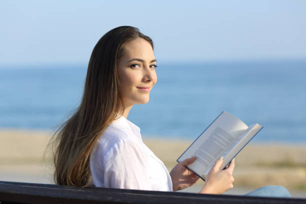 istock Woman reading a book and looking at camera 918094176