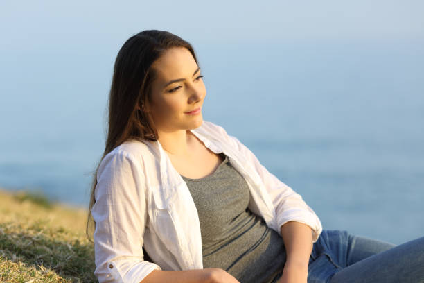 istock Woman contemplating on the grass on a beach 918094220