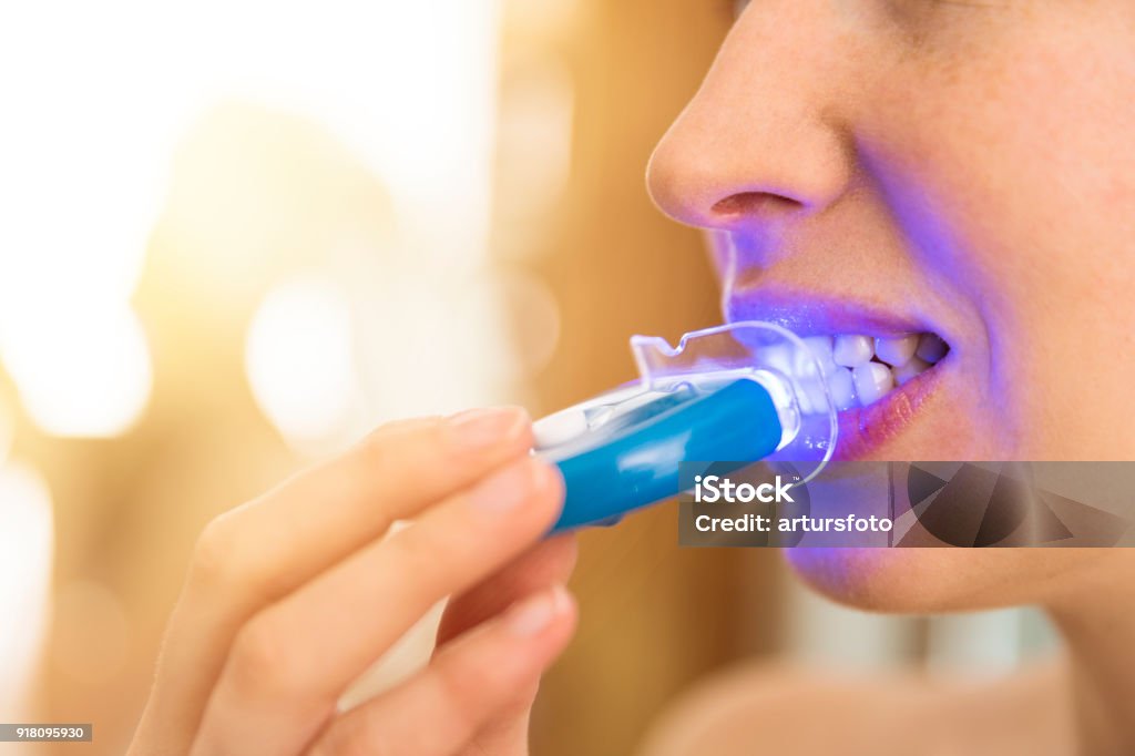 Frau ist Bleaching-Zähne mit speziellen Zahnpasta und LED-Licht zu Hause. Beauty-Konzept - Lizenzfrei Zahnaufhellung Stock-Foto