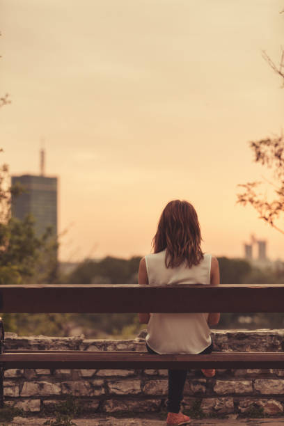 istock Woman sitting on a bench and watching the distant city scenery. 918099320