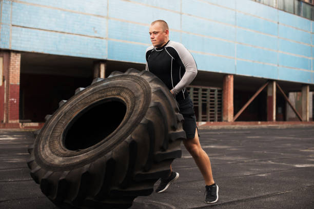 istock Man raises a big tire on the artificial field 918099674