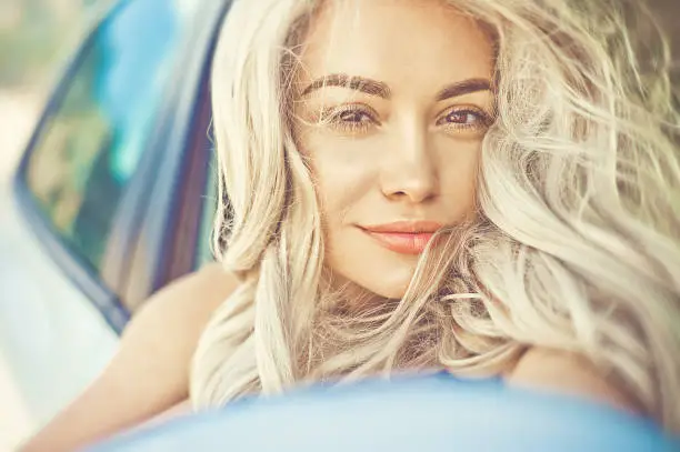 Photo of Beautiful young blonde in car on the beach