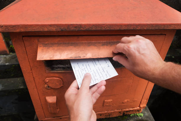 closeup, por um lado masculino, colocando uma carta em uma caixa de correio vermelha. conceito de vintage tipo de comunicação. - red asia send mail - fotografias e filmes do acervo