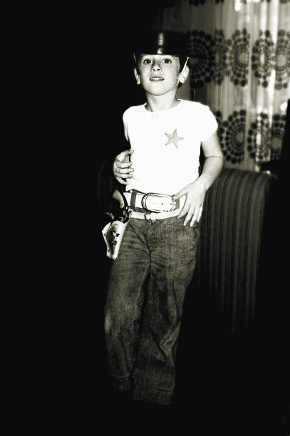 Black and white boy playing the cowboy vintage photo from the seventies of a boy  playing the cowboy at home. cowboy photos stock pictures, royalty-free photos & images