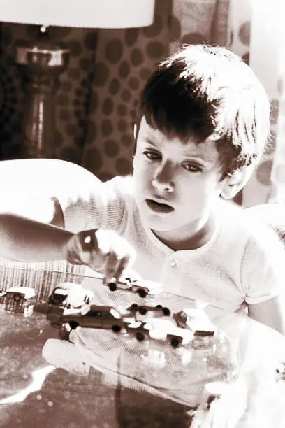 vintage black and white image of a boy playing with his toy cars collection.
