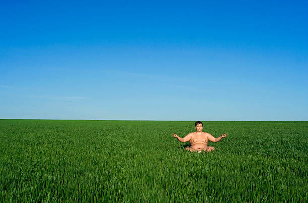 fat man meditation on meadow stock photo