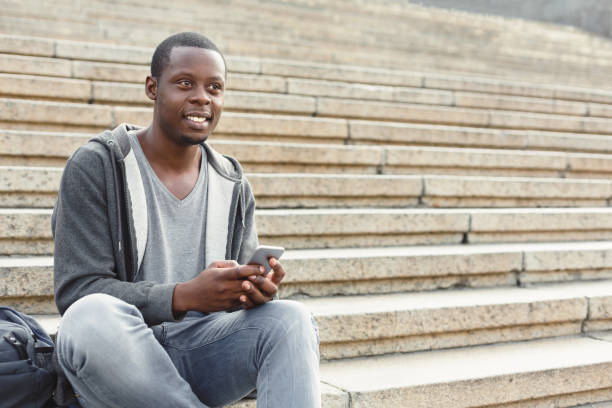 istock Happy african-american student using smartphone outdoors 918128058