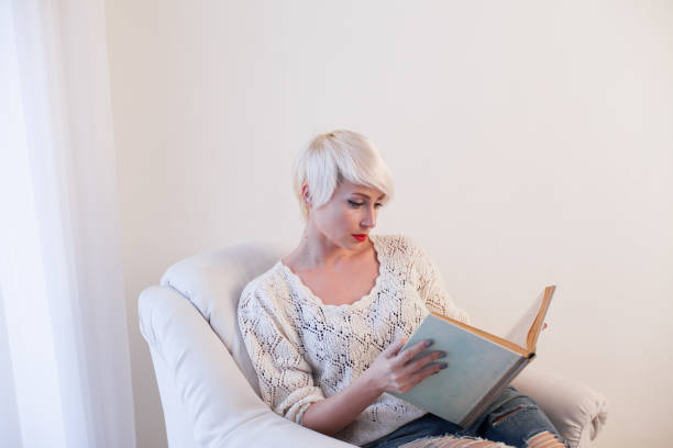 istock girl reading a book in a white armchair 918128464