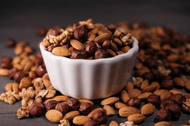 istock The white cup is filled with nuts. Hazelnuts, walnuts and almonds scattered around. Horizontal frame 918132064