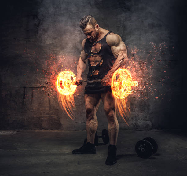 Bodybuilder holding burning barbell. stock photo