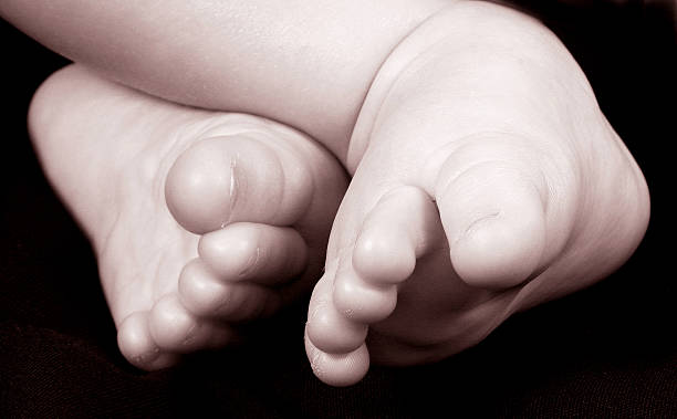 Primo piano del bambino piccolo piedi su sfondo nero, Seppia tono. - foto stock
