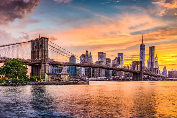 New York City Skyline on the East River with Brooklyn Bridge at sunset.