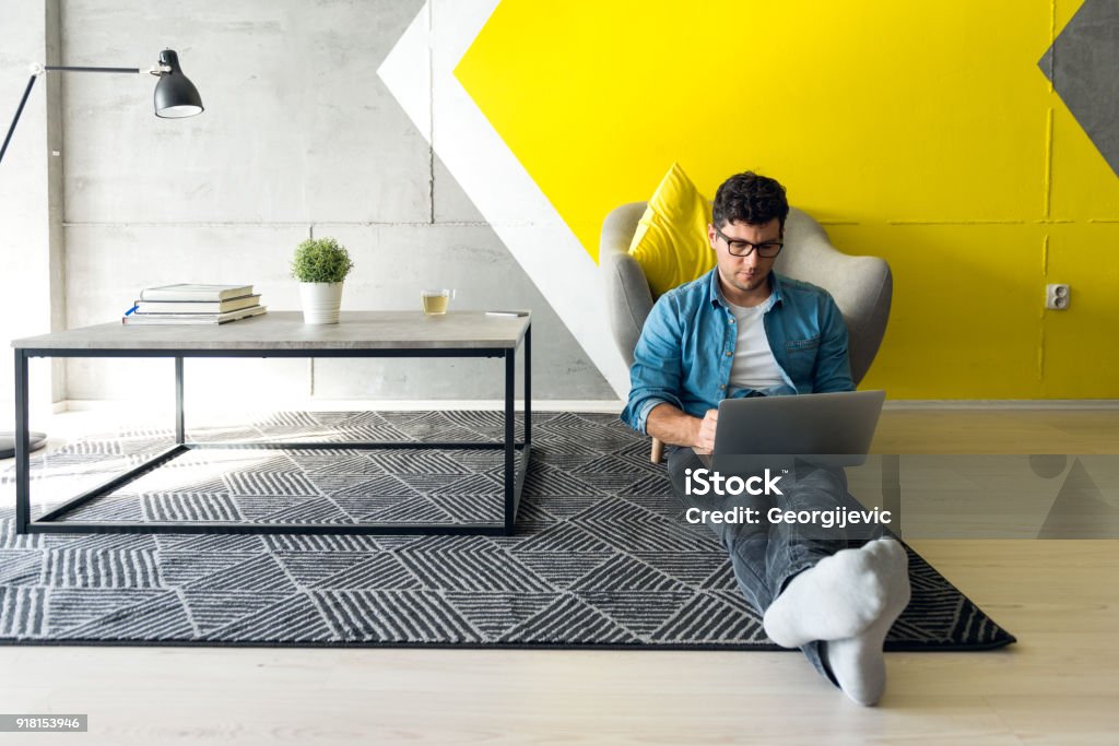 Freelancer Casually dressed guy working in simple and modern space. Dominant color of the space is yellow. Men Stock Photo