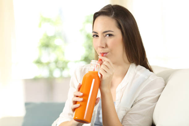 istock Girl drinking a carrot or orange juice from a bottle 918165780