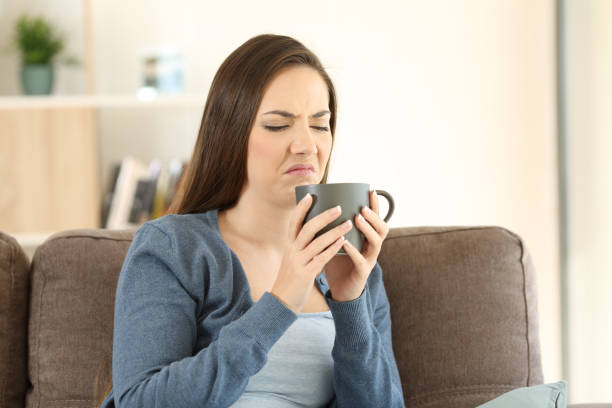 Woman suffering drink bad taste Woman suffering drink bad taste sitting on a couch in the living room at home bad coffee stock pictures, royalty-free photos & images