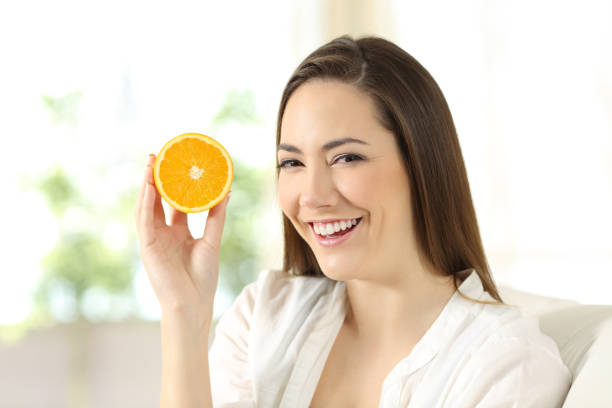 istock Woman showing half orange at home 918166034