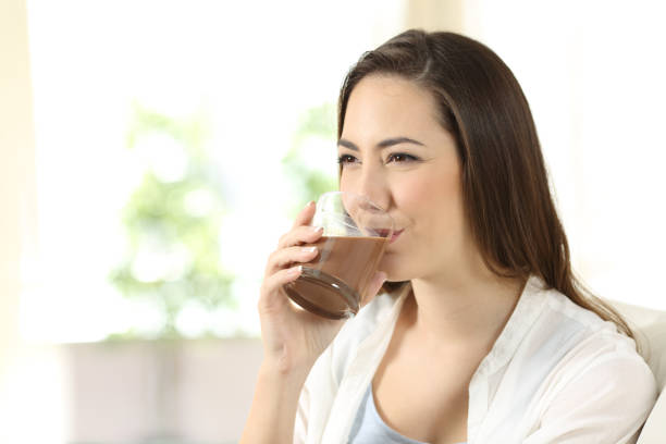 mujer bebiendo un batido de cacao - mujer bebiendo leche fotografías e imágenes de stock