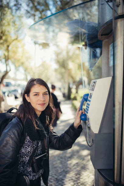 istock Smiling young woman speaking on a public payphone outside.Happy expression.Dialing local number in foreign country,low cost calls for international dials. 918170204