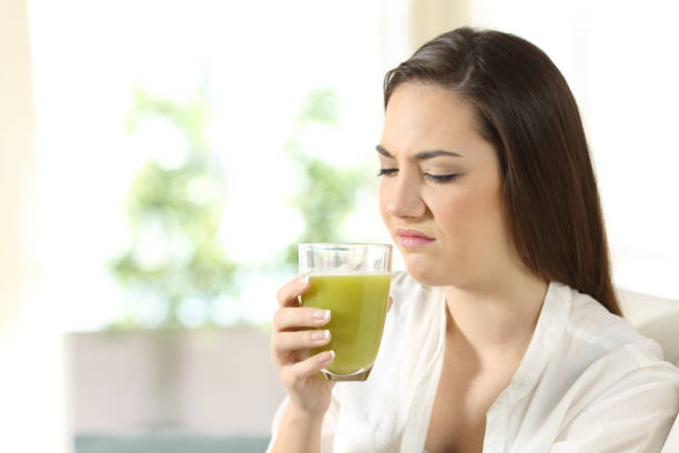 femme dégoûtée, déguster un jus de légumes avec mauvais goût - dieting food rejection women photos et images de collection