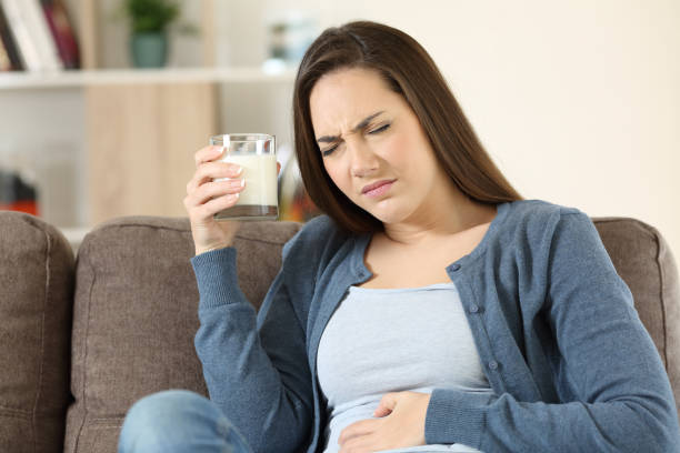 Woman suffering lactose intolerance Woman suffering lactose intolerance sitting on a couch in the living room at home Lactose Intolerance stock pictures, royalty-free photos & images