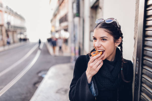 European tourist woman trying out local food.Eating traditional Portuguese egg custard tart pastry dessert pastel de Nata. stock photo