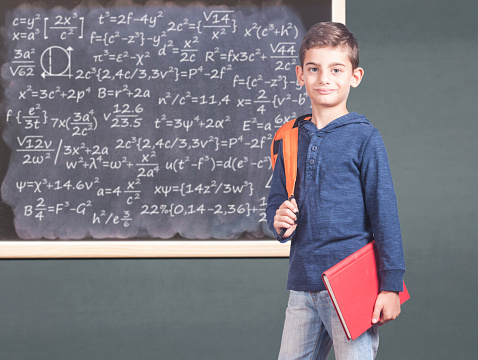 Trendy school boy in front of a blackboard