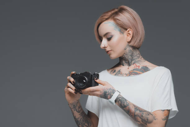 istock beautiful girl with tattoos holding camera isolated on grey 918176746