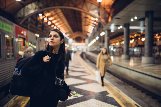 Female traveler searching for directions,waiting for the train/tram,using transportation in foreign country.Urban tourism.Low budget cheap ticket backpacking stock photo