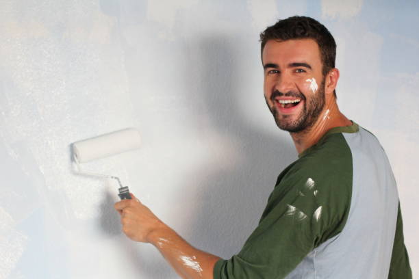 istock Joyful male painting wall with a roller 918201412