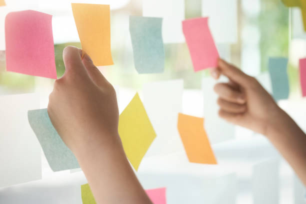 istock Creative business people reading sticky notes on glass wall with colleague working use post it notes to share idea discussing and teamwork, brainstorming concept.Closeup shot. 918205648