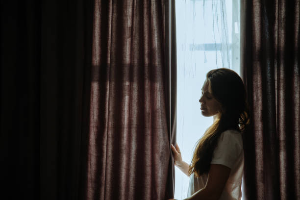 istock woman stand near window in sunlight 918218690