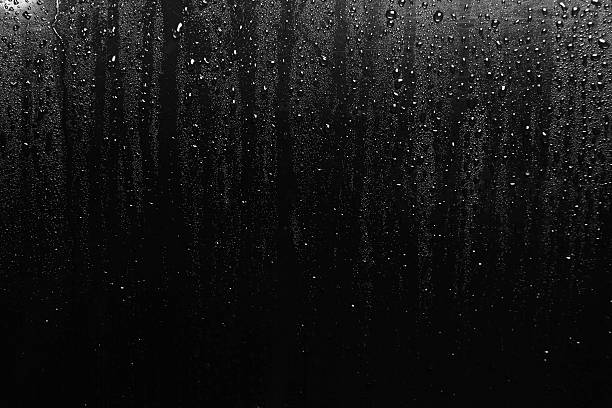 water droplets form on black metal surface - druppels stockfoto's en -beelden