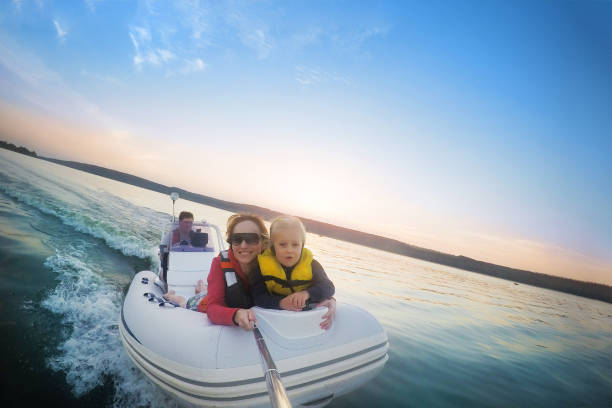 Happy couple with daughter riding boat on lake or river at sunset. Pair  with child making selfie while water activity.  Happy family  recreation and adventure concept. Beautiful travel background Happy couple with daughter riding boat on lake or river at sunset. Pair  with child making selfie while water activity.  Happy family  recreation and adventure concept. Beautiful travel background. family motorboat stock pictures, royalty-free photos & images