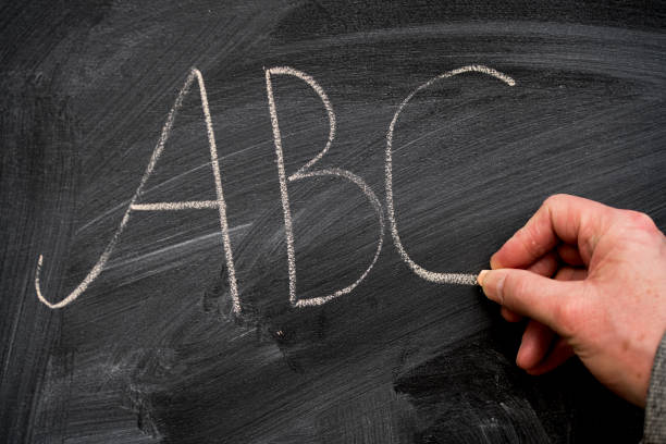 istock hand of teacher writing alphabet on blackboard 918237452