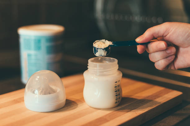 mère faisant de lait maternisé en bouteille de lait - formula photos et images de collection