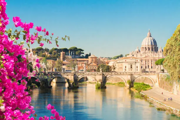 St. Peter's cathedral over bridge and river with flowers in Rome, Italy