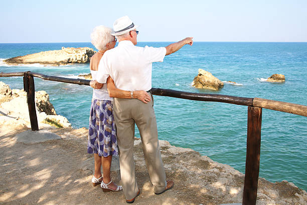 istock Elderly couple standing by a railing pointing to the ocean 91824394