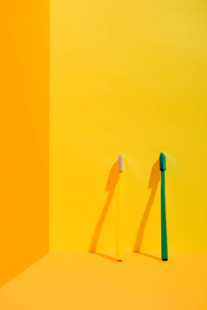istock green and yellow toothbrushes at orange wall 918245260
