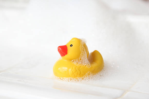 caoutchouc duckie sur le bord de la baignoire avec des bulles - duckie photos et images de collection