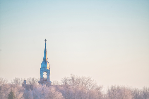 A church steeple in the distance during a sunrise in winter.