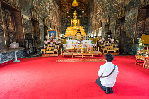 Bangkok, Thailand. January 2018. Faithful pray in front of the golden statue of Buddha in Wat Suthat temple, Bangkok