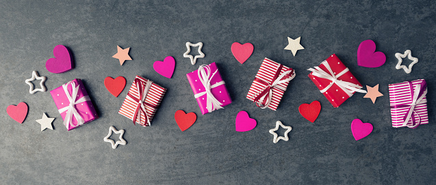 Flat lay of gift boxes and Valentines hearts on dark stone background.