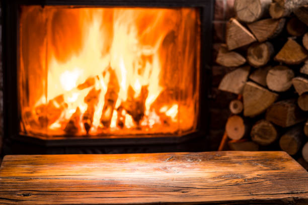 istock Old wooden table and fireplace with warm fire. 918259992