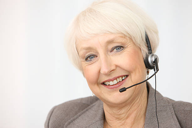 Smiling mature woman with headset. Office buildings in the background.