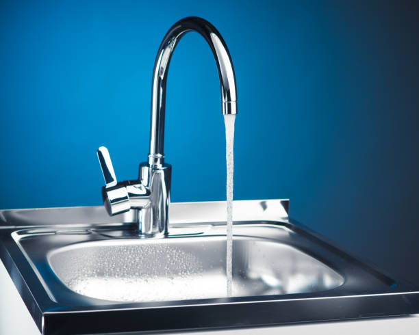 istock kitchen faucet with flowing water, blue background 918266596