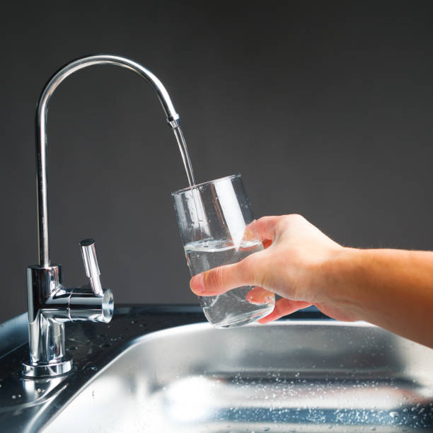 istock hand pouring a glass from water filter tap 918266928