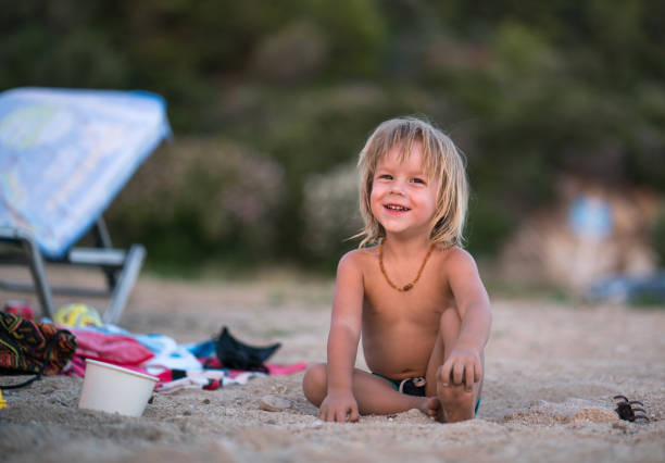istock Happy little boy relaxing on the sand at the beach. 918273396