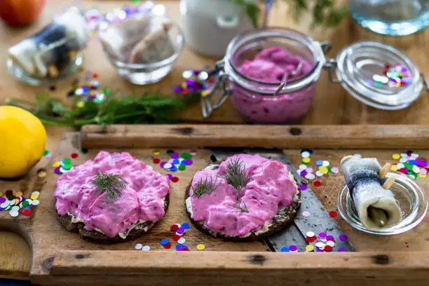 Carnival hangover breakfast with herring salad and roll pug on a rustic-cold wooden board