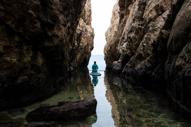 istock Woman kneeling on a stand up paddle board among the cliffs 918277050